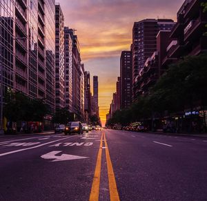 City street and buildings against sky during sunset