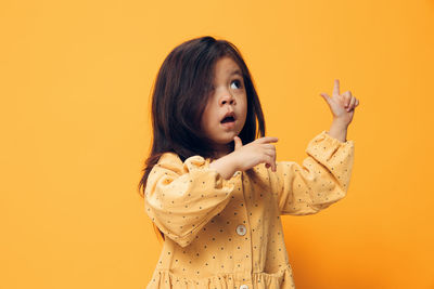 Portrait of young woman holding gift against yellow background