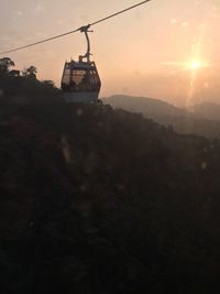 Overhead cable car over mountains against sky during sunset