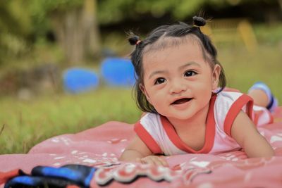 Cute smiling girl lying on picnic blanket