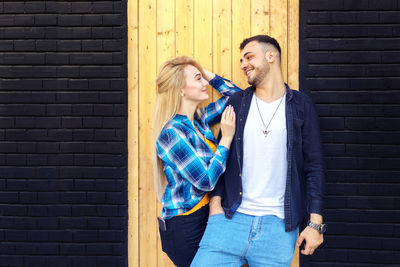 Young couple standing against wall