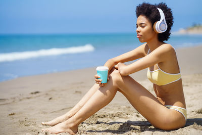 Young woman drinking water at beach