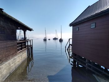 Wooden house by sea against sky