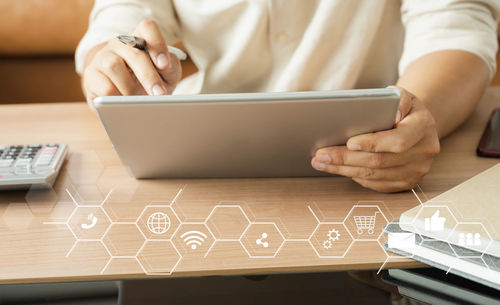 Midsection of man using mobile phone on table