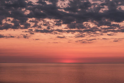 Scenic view of sea against dramatic sky during sunset