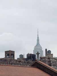 Empire state building and other houses against sky