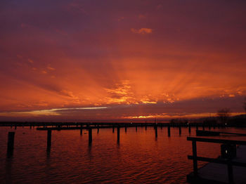 Pier over sea against orange sky