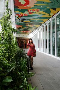 Woman standing by plants against building