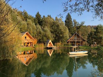 Houses by lake and trees against sky