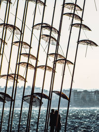 Couple standing by structure with umbrellas by sea