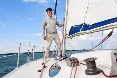 People on sailboat sailing in sea against sky