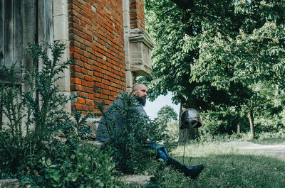 Rest of viking warrior near old brick castle and tall tree. sword and helmet. person