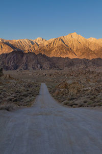 Movie road in alabama hills leading into the sierra nevadas lit by brilliant morning sun