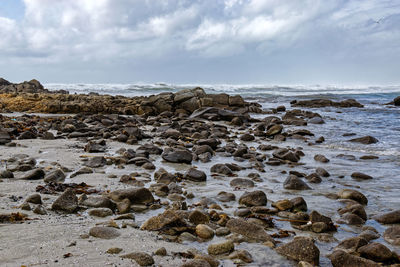 Scenic view of rocks on beach against sky