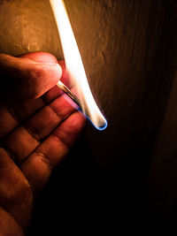 Close-up of hand holding burning matchstick