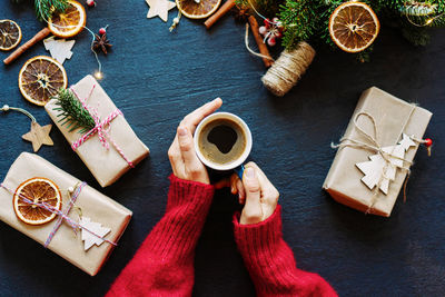 Top view of female hands in a beautiful cozy sweater holding a mug of coffee, christmas decor 