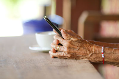 Close-up of hand holding coffee cup on table