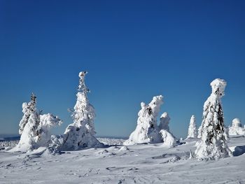 Scenic view of snow covered landscape against clear blue sky