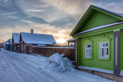 Houses by road against sky during winter