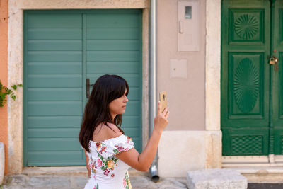 Young woman, tourist, using mobile phone, taking photos in old town.