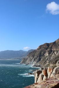 Scenic view of sea and mountains against blue sky