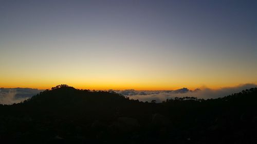 Scenic view of silhouette mountains against orange sky