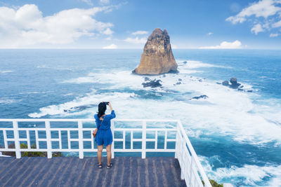 Rear view of woman looking at sea against sky