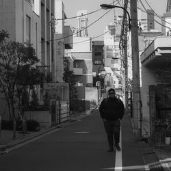 Rear view of man walking on street amidst buildings