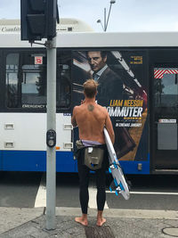 Rear view of shirtless man standing on railroad station platform