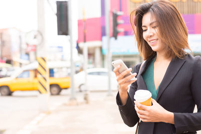 Young woman using mobile phone in city