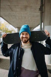Portrait of young man holding skateboard