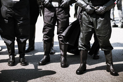 Low section of security guards standing on street during sunny day