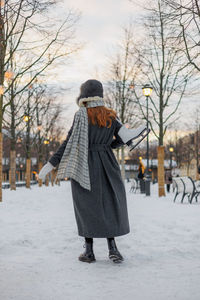 Rear view of woman standing on snow covered field