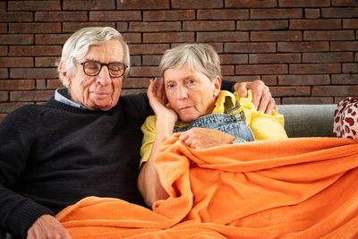 Portrait of smiling senior couple sitting on sofa at home