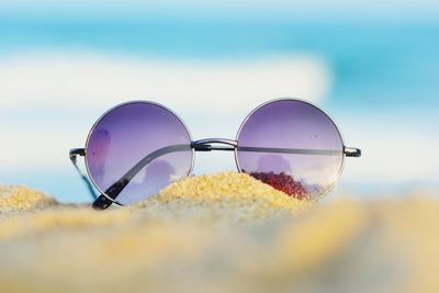 Close-up of sunglasses on beach against sky