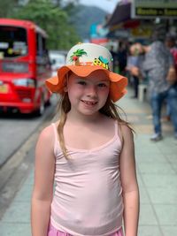 Portrait of cute girl standing on street in city