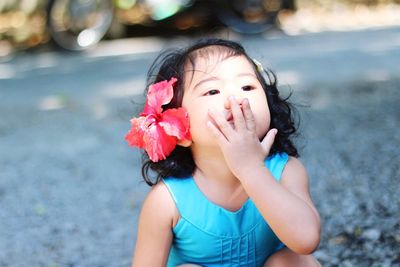 Close-up of cute baby girl sitting on road