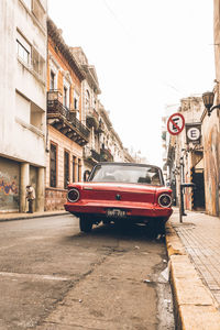 Cars on street by buildings against sky