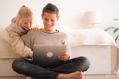 Young woman using digital tablet while sitting on sofa at home