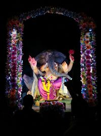 Rear view of silhouette boy standing in front of ganesha idol