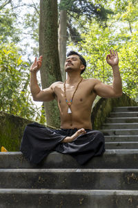 Young man doing meditation on a stairway in a forest, mexico