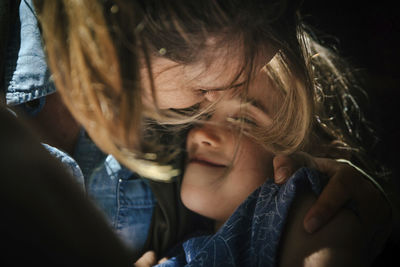 Close-up of mid adult mother embracing smiling daughter