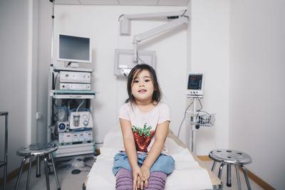 Portrait of girl sitting on bed at hospital