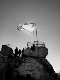 Low angle view of people on rock against sky