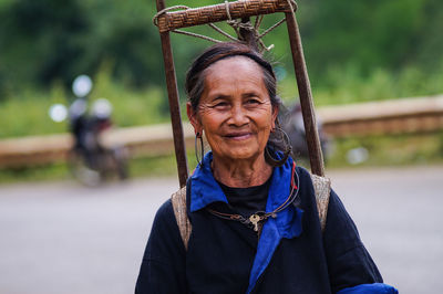 Senior woman carrying wooden equipment on road