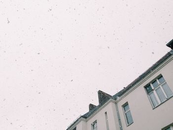 Low angle view of building against sky during snowfall