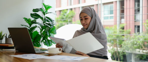 Young businesswoman using laptop while sitting on table