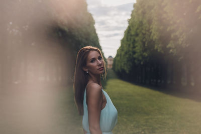 Portrait of young woman standing against sky during sunset