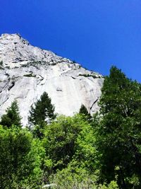 Low angle view of rocky mountains against clear blue sky