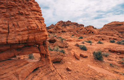 Rock formations on landscape against cloudy sky